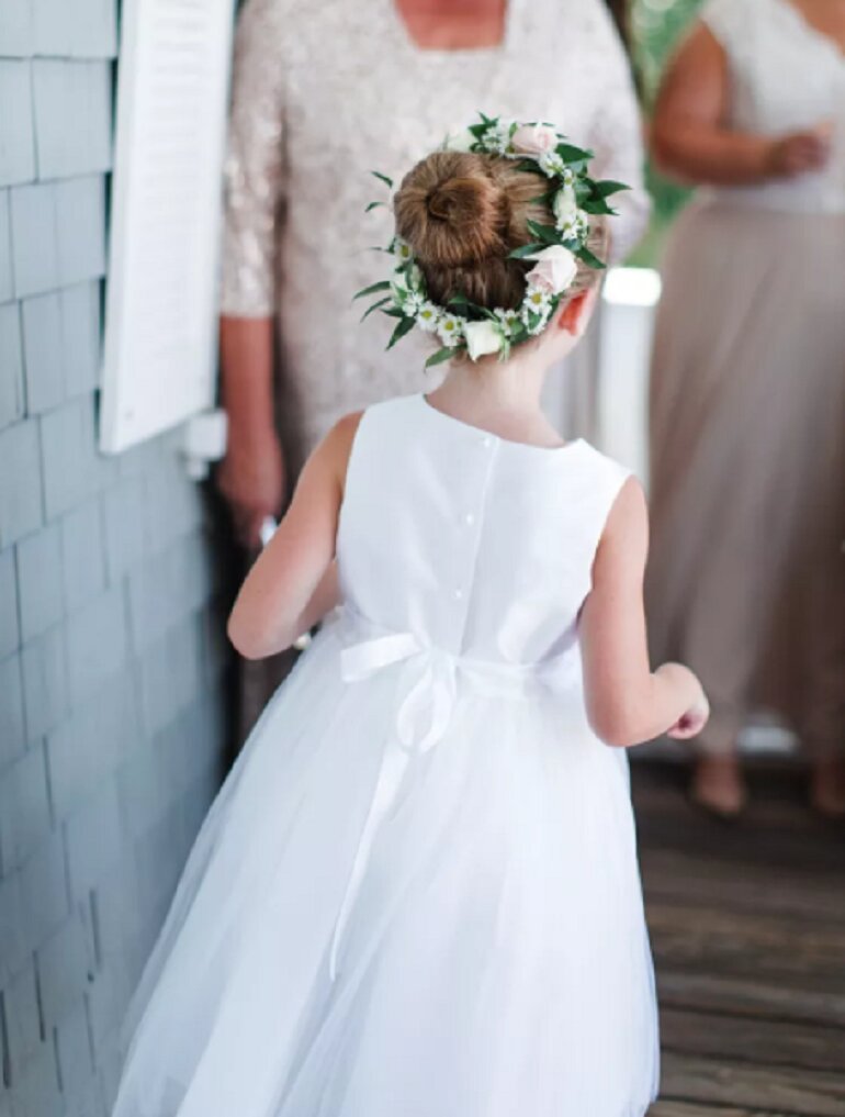 Hình ảnh bé gái tóc dài búi cao và đội chiếc vòng hoa giống với loài hoa mà cô dâu đang cầm sẽ vô cùng tuyệt vời. Đây là kiểu tóc dễ làm và giúp các bé trở nên gọn gàng, tròn trịa hơn!
