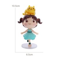 Tượng em bé gái váy xanh đội mèo vàng.